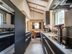 A modern kitchen with a wooden ceiling, a dining area, and a view of the outdoors. - Chalet Steinbock by Arosa Holiday Appartement/Fewo, Bad, WC, 3 Schlafräume by Interhome (Arosa)