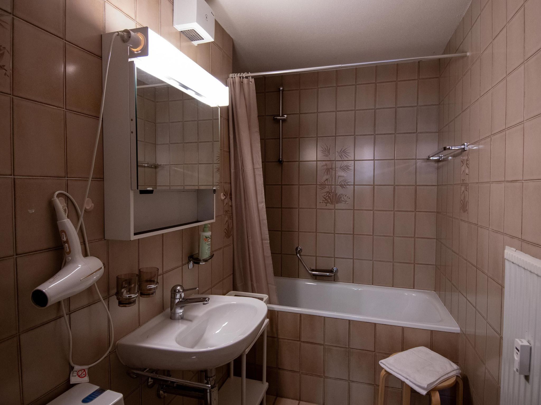 Een badkamer met een wastafel, spiegel, douche en handdoekrek.