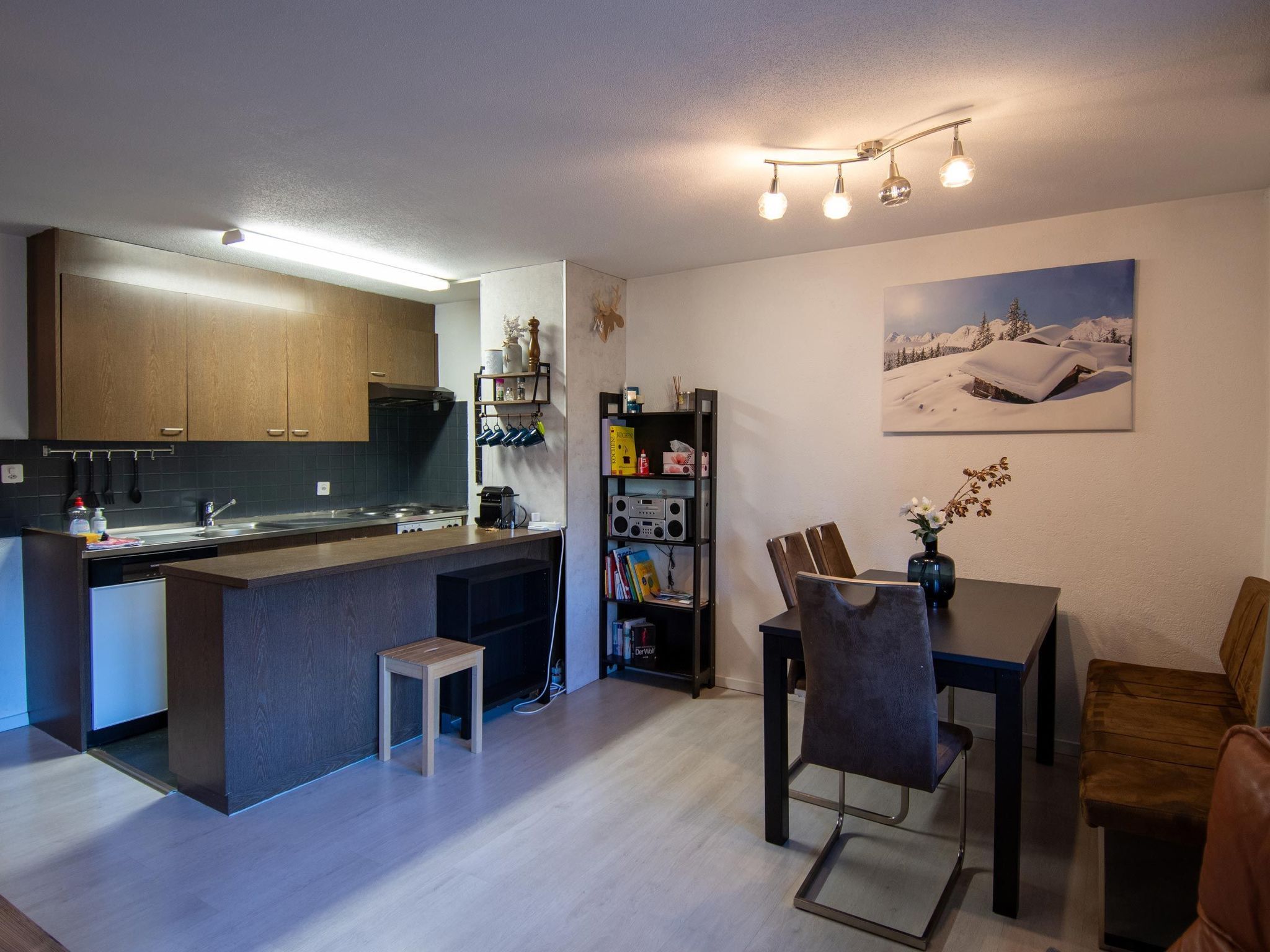 Una cocina moderna con armarios de madera, una estufa integrada y una zona de comedor con mesa y sillas.