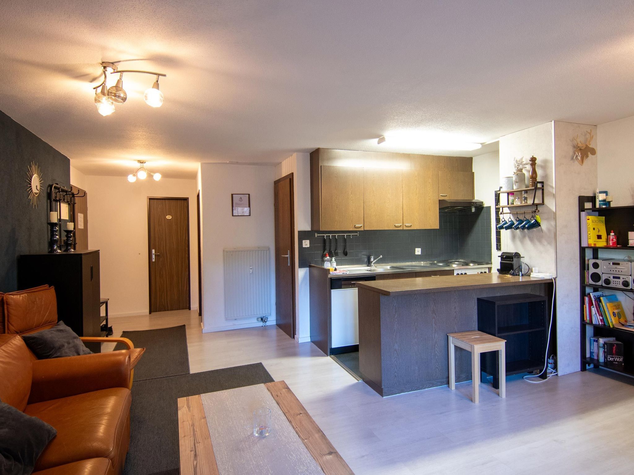 Een moderne keuken met een centraal eiland, een eetgedeelte met een leren bank en een woonkamer met een open haard.