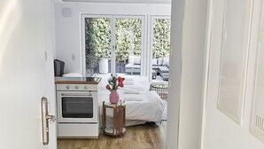 Et hotelværelse med tekøkken, seng, et lille bord med en vase og udsigt til det fri.
