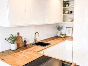 A modern kitchen with white cabinets, a wooden countertop, a black sink, and a stainless steel dishwasher. - mit Infinity-Pool by Interhome (Munich)