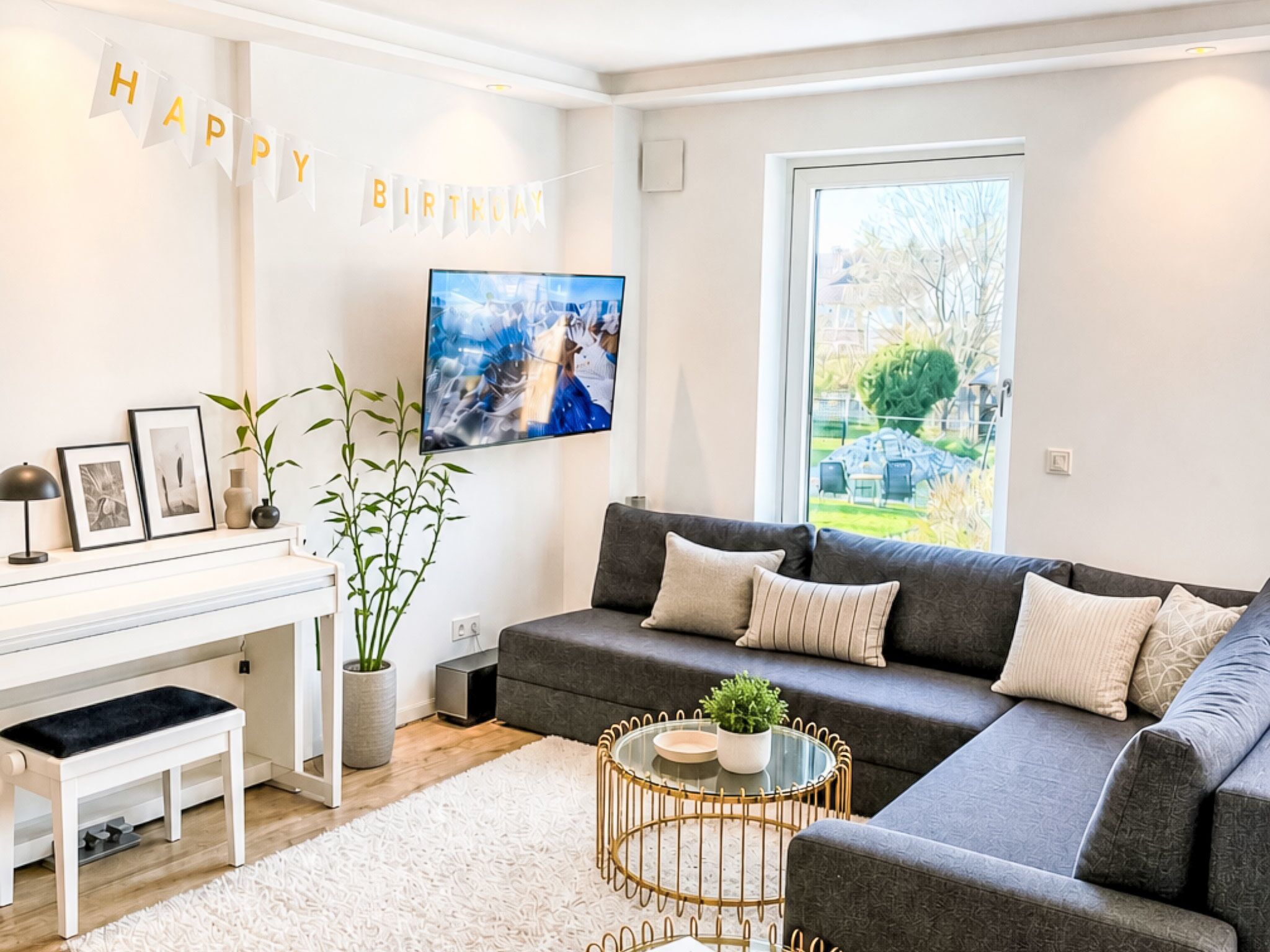 A modern living room with a sofa, a coffee table, a TV, and a piano.