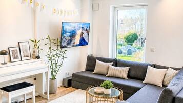 A modern living room with a sofa, a coffee table, a TV, and a piano.