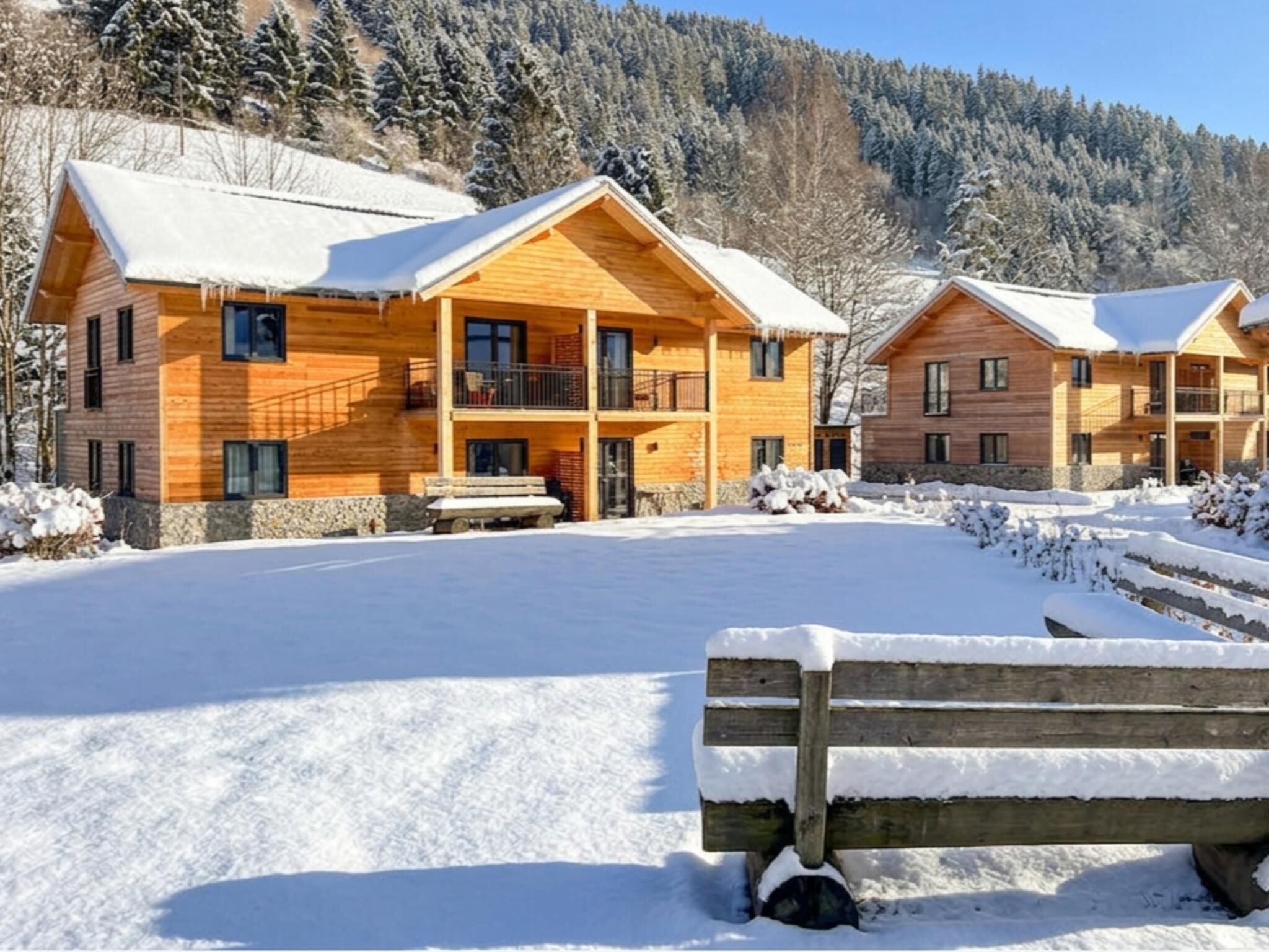 Un bâtiment de style chalet en bois, doté d’un balcon, situé dans un paysage enneigé sous un ciel dégagé.