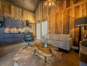 Ein rustikales Interieur mit Holzbalkendecke, einer Küchenzeile, einem Sofa und einem Couchtisch.
