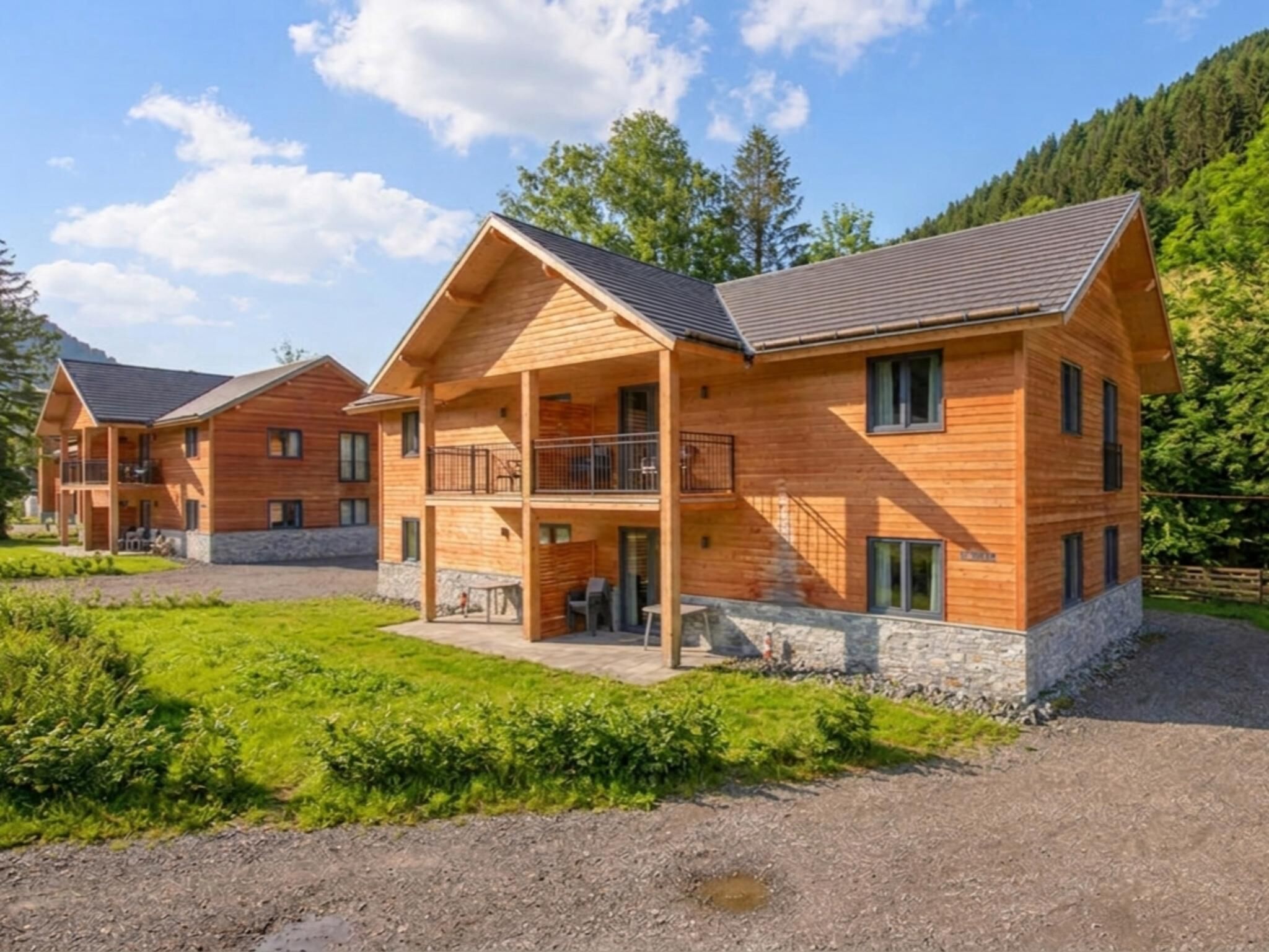 Eine Holzhütte mit Balkon, umgeben von Grün und blauem Himmel.