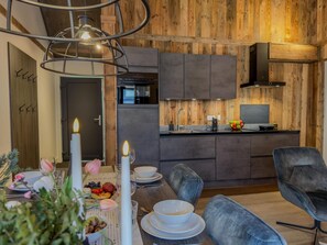 Une cuisine moderne agrémentée d’éléments en bois, un coin repas avec une table dressée pour deux personnes et un espace salon confortable.