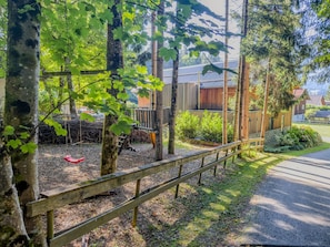 A wooden fence, a swing, and a pathway leading to a building with a metal roof. - Spacious holiday apartment by a lake in the Alps (Hermagor-Pressegger See)