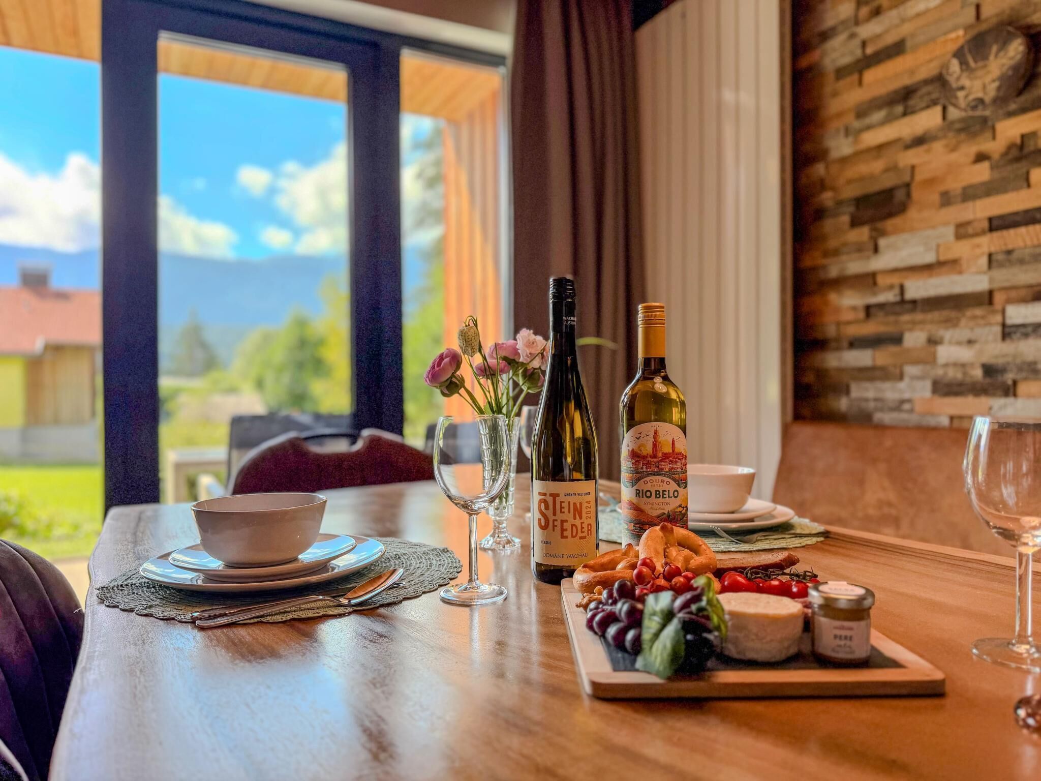 A dining table with a bottle of wine, glasses, and a plate of food.