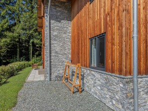 Un edificio moderno con facciata in pietra e pannelli di legno, un tubo metallico e un cavalletto in primo piano.