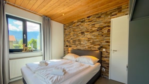 Een slaapkamer met een bed, een raam met uitzicht en een houten plafond.