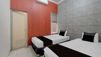 A hotel room with two beds, a window with blinds, a door, and a wall with a brick pattern.