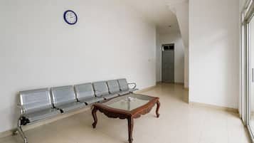 A waiting area with a bench, a glass-top table, and a wall clock.