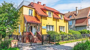 Ein gelbes Gebäude mit rotem Dach, einem verschlossenen Eingang und einem gepflasterten Weg.