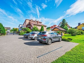 A paved driveway with two parked cars, a house with a red roof, and a well-maintained lawn. - Apartment Zenit by Interhome (Darlowo)