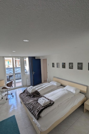 A hotel room with a large bed, a desk, and a chair. There is a door leading to a balcony. - Alpina Peaks Appartement/Fewo Appartement/Fewo by Interhome (Saas-Fee)