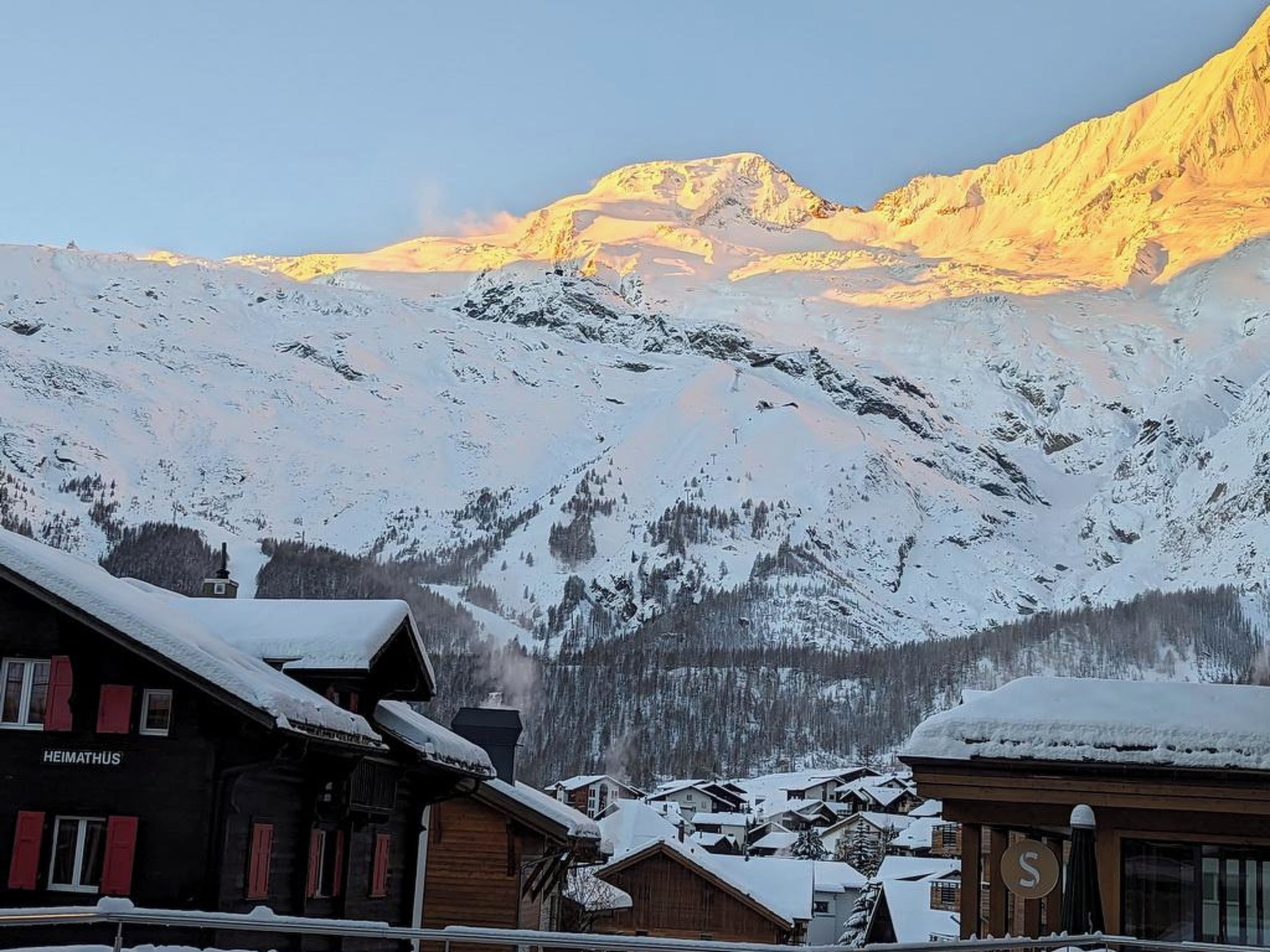 A mountain village with snow-covered buildings and a prominent mountain in the background.