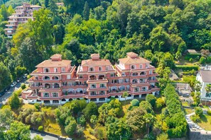 A multi-story building with a symmetrical facade, surrounded by dense greenery. - Manuela's Apartment Stresa Next to Center Lake View Terrace (Stresa)