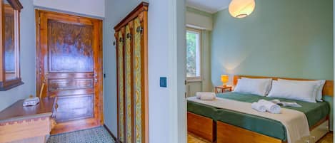 Una habitación con puerta de madera, una cama con cubrecama verde y una lámpara colgante.
