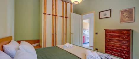 Una habitación de hotel con cama, armario, cómoda y una lámpara en el techo.