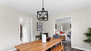 Un comedor con mesa de madera, bancos y una lámpara colgante.