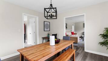 A dining area with a wooden table, benches, and a black pendant light.