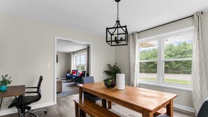 Un coin repas avec une table en bois, des chaises et un luminaire suspendu.