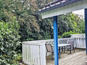 A covered outdoor deck with a table and chairs, surrounded by a white fence and dense foliage. - Vacation home Nina by Interhome (Extertal)