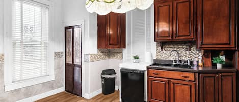 A kitchen with wooden cabinets, a dishwasher, and a trash can.