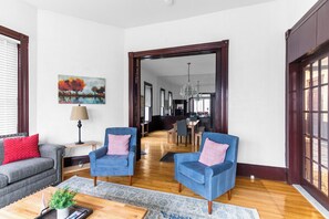 A living room with two blue armchairs, a grey sofa, a wooden coffee table, and a painting on the wall.