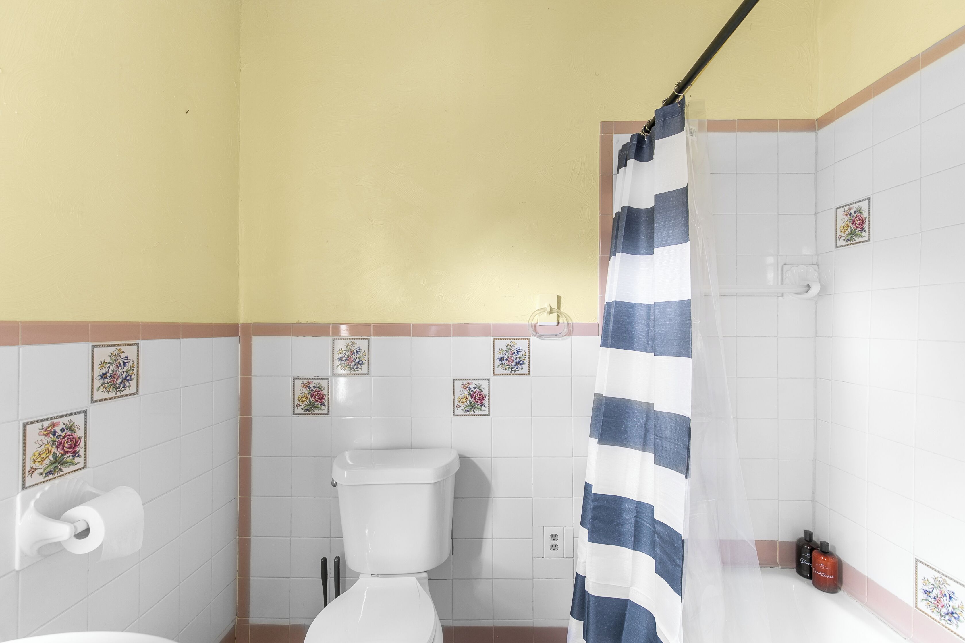 A bathroom with a toilet, a shower curtain, and a sink with toiletries.