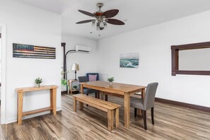A dining area with a wooden table and benches, a ceiling fan, and artwork on the walls.