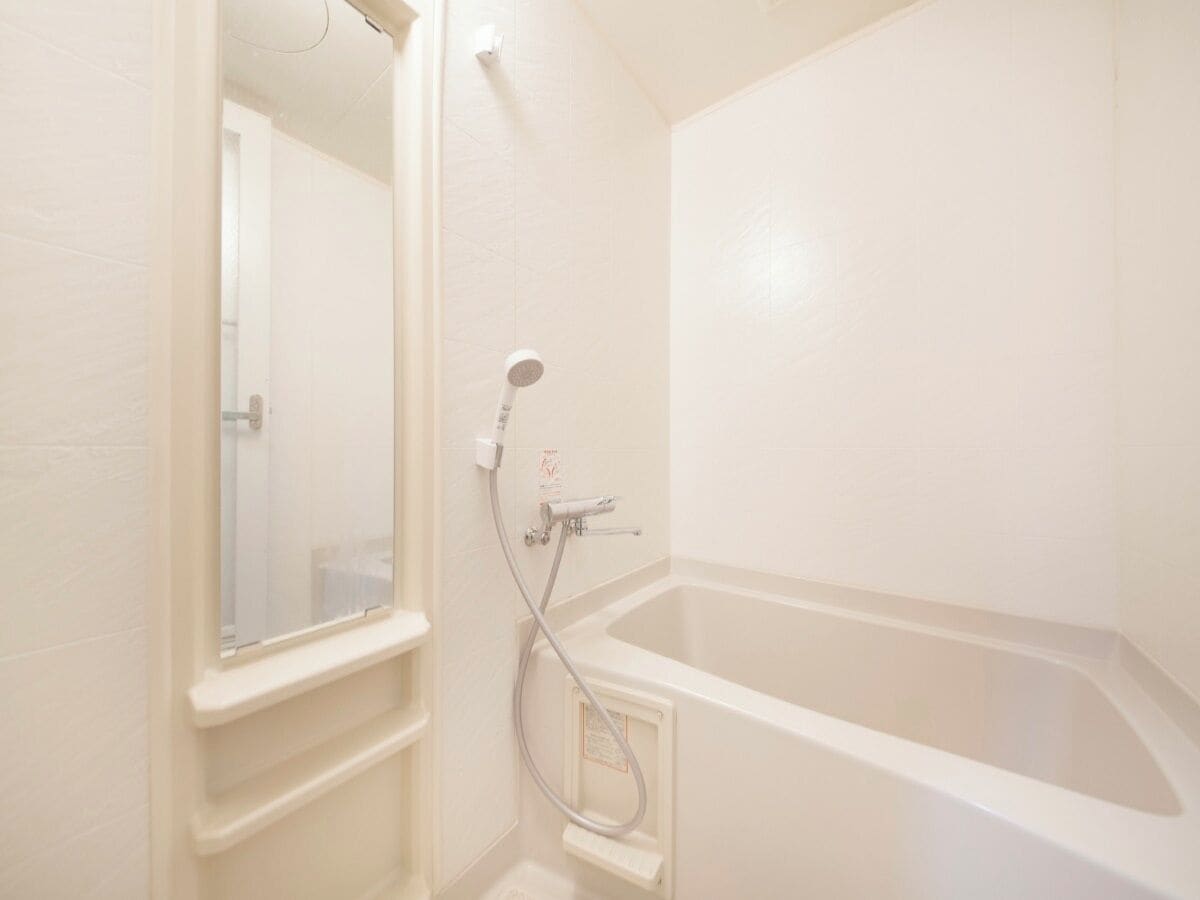A bathroom with a bathtub, a shower, and a mirror.