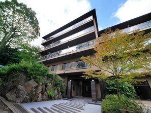 Ein mehrstöckiges Gebäude mit moderner Architektur, mit Balkonen und einem begrünten Eingangsbereich.