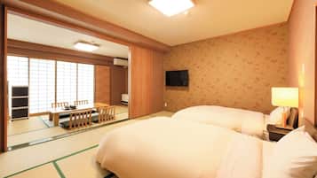 Una habitación japonesa tradicional con suelo de tatami, una cama futón, un televisor y una puerta corrediza que da a un comedor.