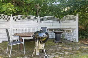 En uteplats med ett bord, stolar, en grill och ett arbetsbord för grillen.