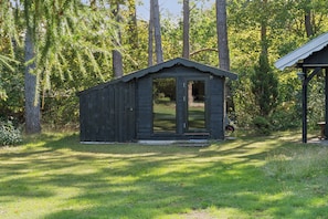 A small wooden cabin with a door and windows, surrounded by grass and trees. - Charming holiday home in beautiful Asserbo (Liseleje)