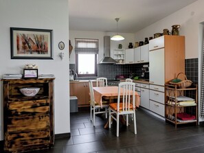 Eine moderne Küche mit Esstisch, Stühlen und verschiedenen Küchengeräten.