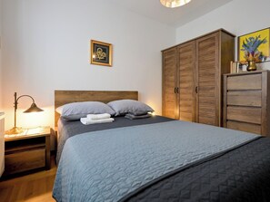 Ein Schlafzimmer mit einem Bett, einem Nachttisch, einer Lampe, einem Kleiderschrank und einem gerahmten Bild an der Wand.
