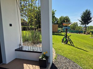 Un espacio exterior moderno con un banco de madera, una planta en maceta y una bicicleta.