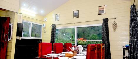 En matplats med ett bord för fyra personer, ett fönster med utsikt över grönområden och en takfläkt.