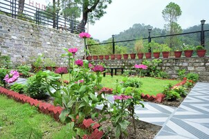 Un jardín con muro de piedra, plantas en macetas y un sendero con diseño.