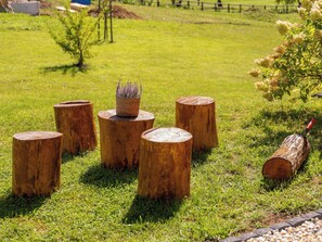 Een grasveld met vijf houten boomstronken in een halve cirkel, een kleine potplant op een van de stronken en een boomstam op de grond.
