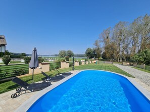Ein Pool mit Liegestühlen und Blick auf einen See.