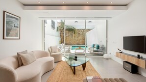 Una sala moderna con un sofá, una mesa de centro de vidrio y un televisor de pantalla plana.