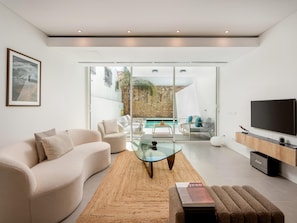 A modern living room with a sofa, a glass coffee table, and a flat-screen TV. - Luxury Villa, Sea View and Pool, Central Lagos (Lagos)