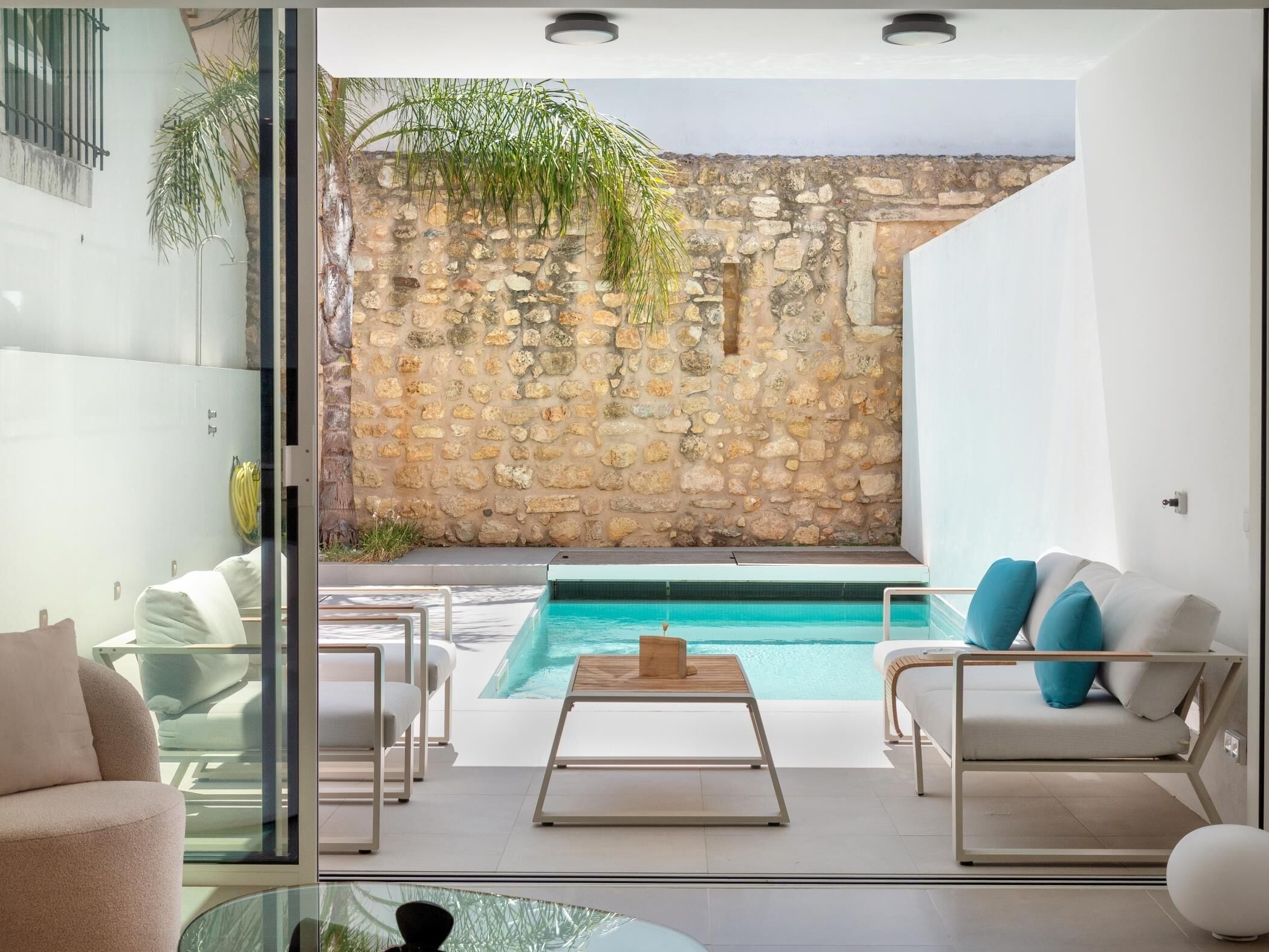 A modern interior with a pool, stone wall, and outdoor seating.