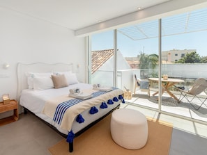 A modern bedroom with a large bed, a bedside table, a nightstand, a window with a view of the city, and a balcony with outdoor furniture. - Luxury Villa, Sea View and Pool, Central Lagos (Lagos)