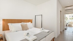 Habitación de hotel moderna con una cama grande, cabecera de madera y vistas al exterior.